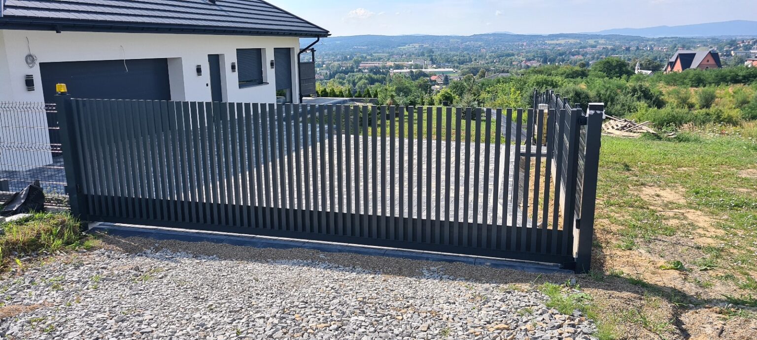 brama Comb Standard z aluminium Euro Fences. Widok na panoramę Jasła w tle oraz budynek mieszkalny