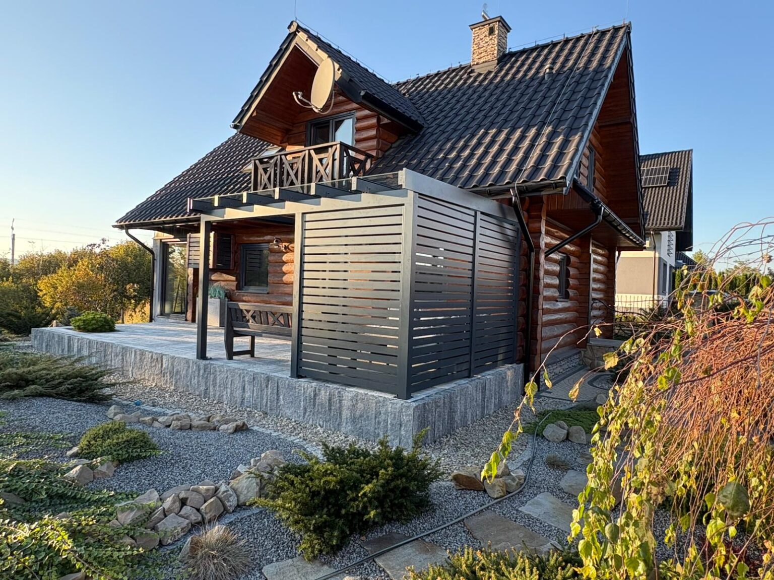 Pergola aluminiowa, zadaszenie ogrodowe, na pierwszym planie krzewy ogrodowe, w tle niebo